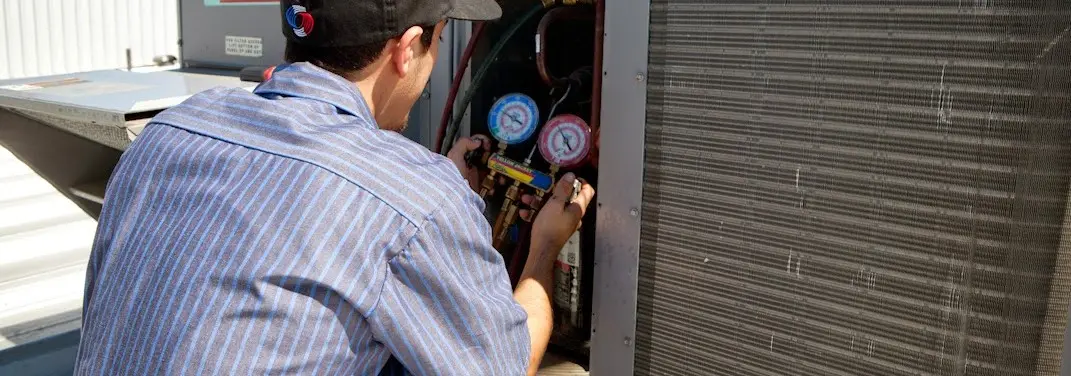 HVAC technician servicing a condenser unit in Imperial