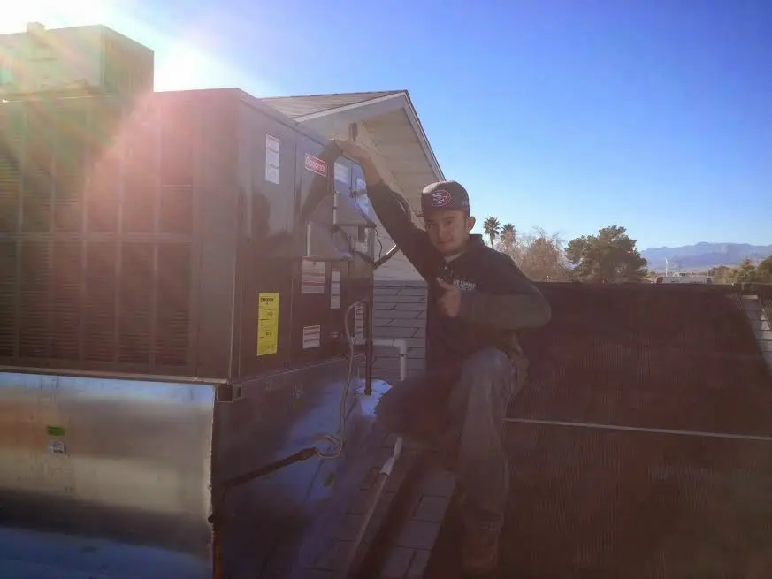 HVAC technician performing Air Duct Cleaning on a rooftop unit in Imperial